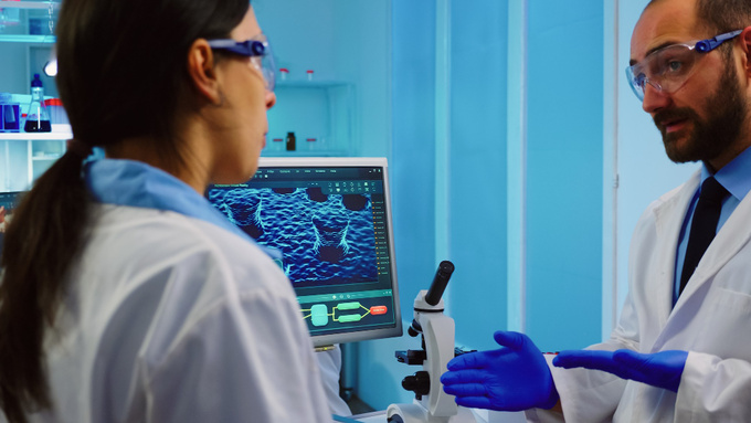 professional-chemists-analysing-vaccine-development-using-touchscreen-display-equipped-laboratory-overwork