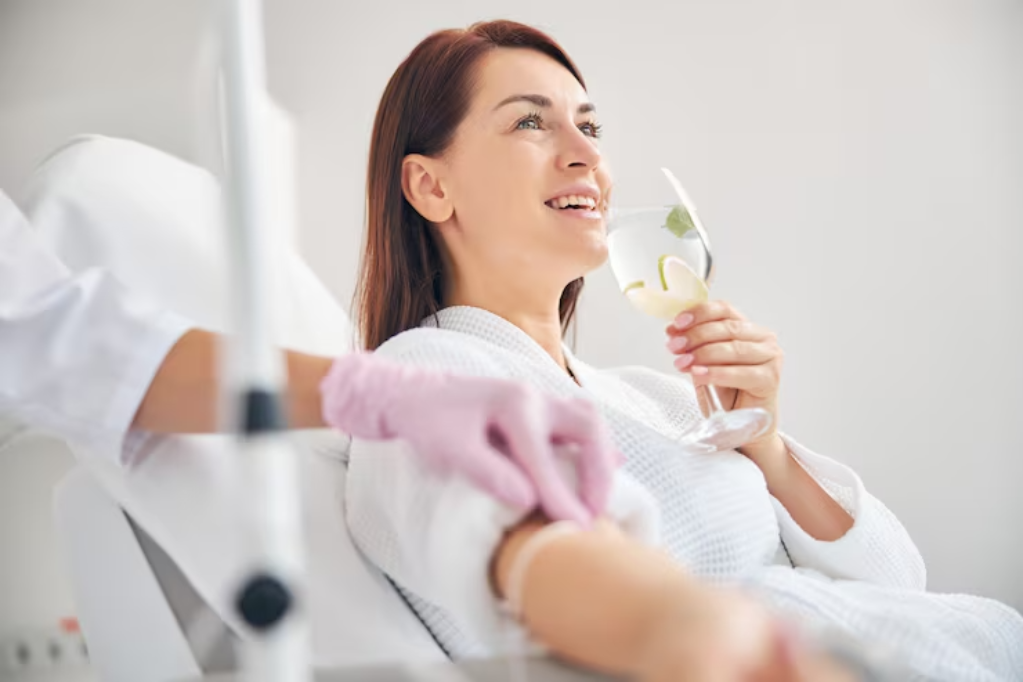 A blurred image of a smiling blonde woman in a white bathrobe holding a wine glass containing clear water and a slice of lemon