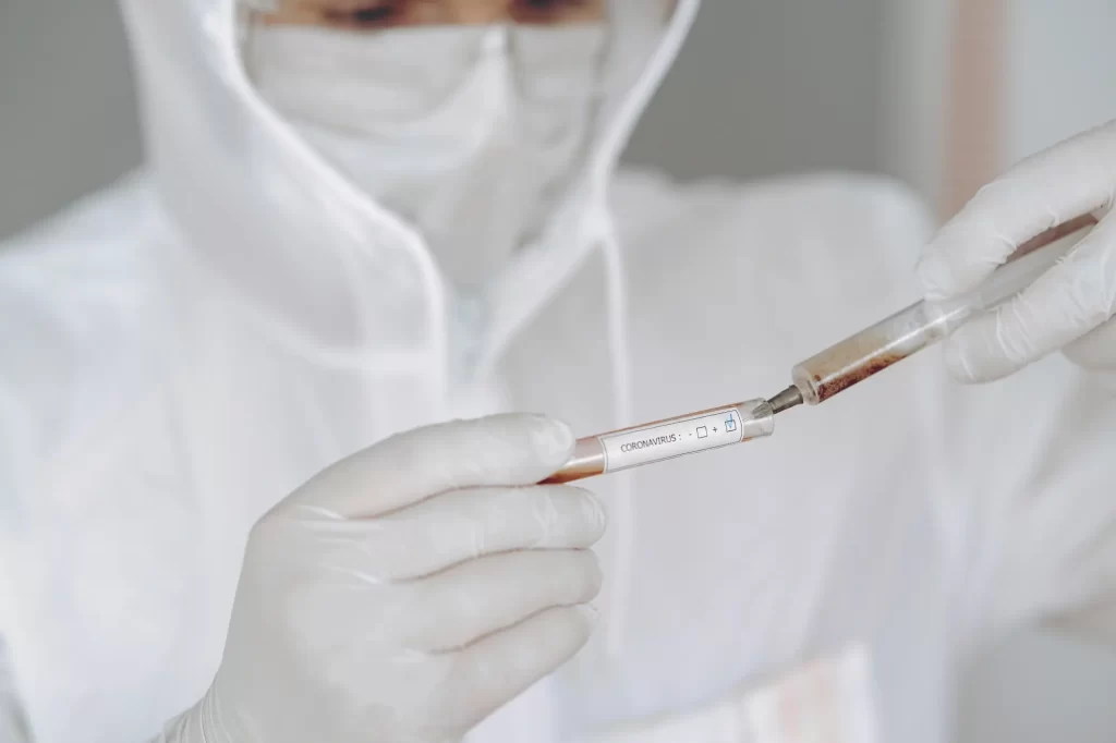 Close-up of syringe and petri dishes with bacterial cultures on white surface in medical laboratory setting