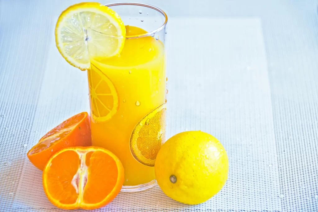 A tall glass of yellow juice, garnished with a lemon slice on the rim