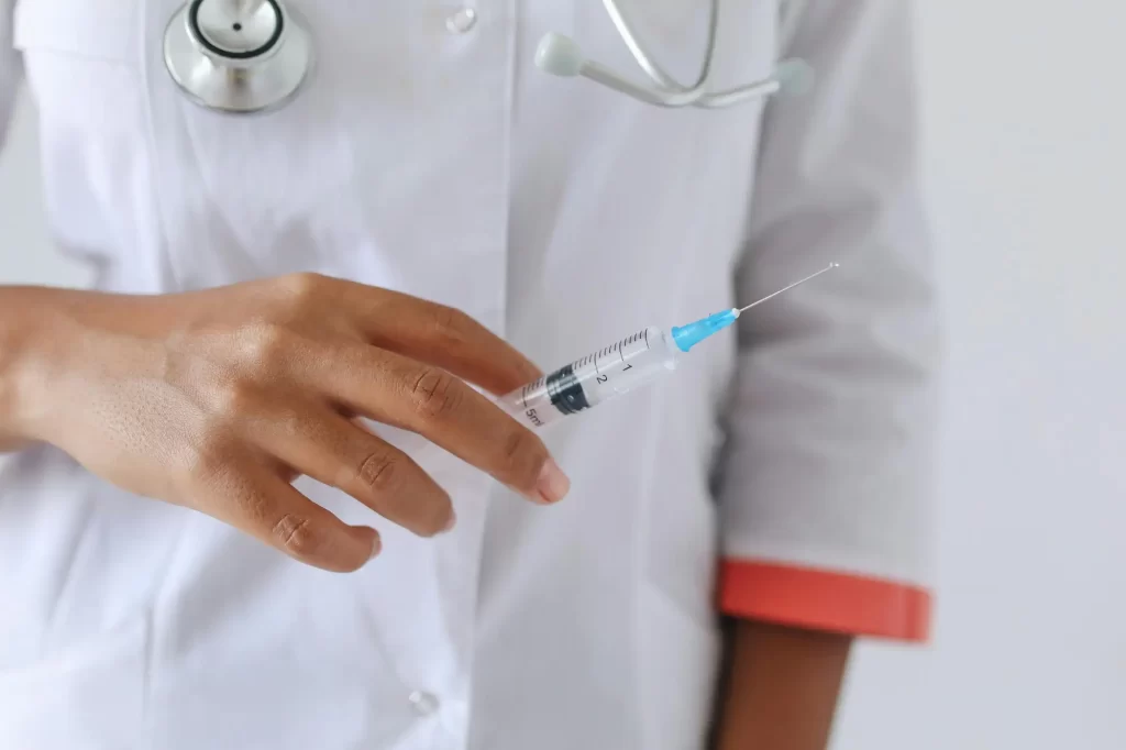Doctor or nurse holding a syringe filled with clear liquid