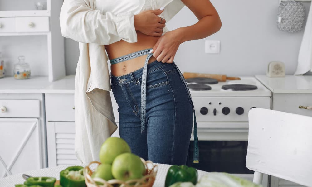 Fit girl using measuring tape on her hips